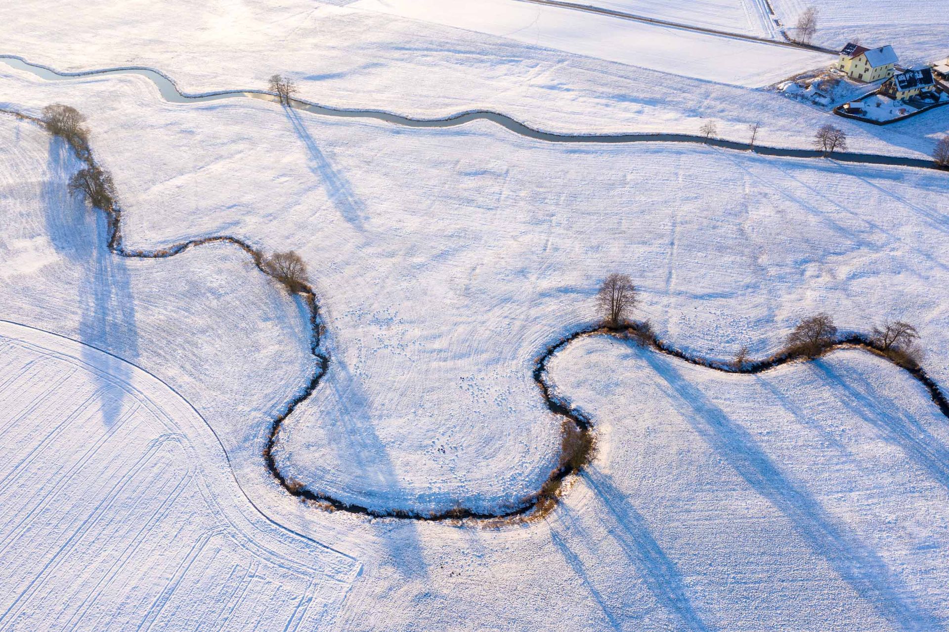 Ein Bach fließt durch die verschneite Winterlandschaft